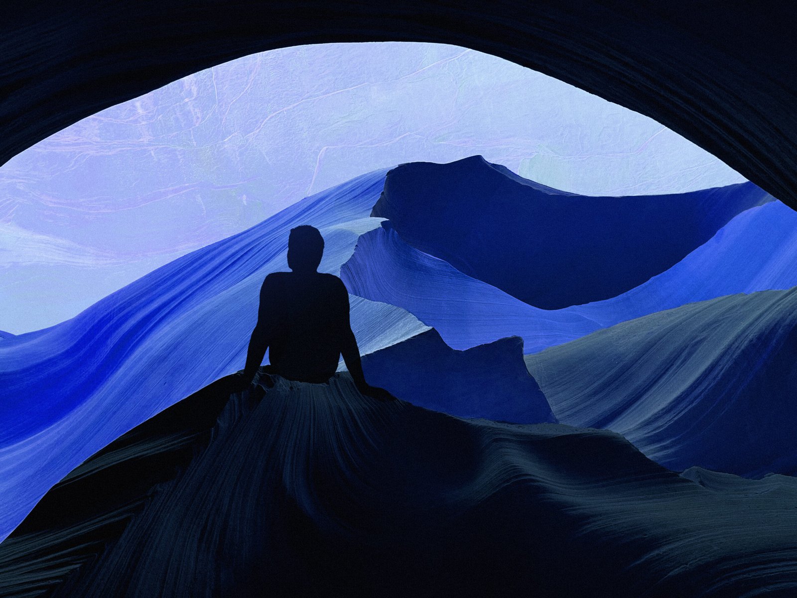 Silhouette of a person seated at the mouth of a blue cave, gazing over an abstract, undulating landscape; contemplative mood, a metaphor for inner exploration of attention and the meaning of the ADHD label.