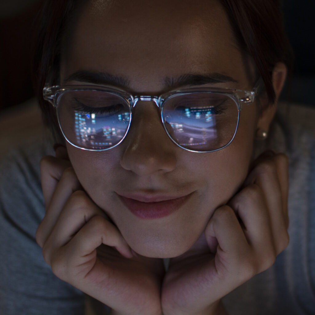 Woman staring into a screen with digital icons reflected in her glasses, illustrating the paradox of attention seeking and ADHD through a psychoanalytic lens.