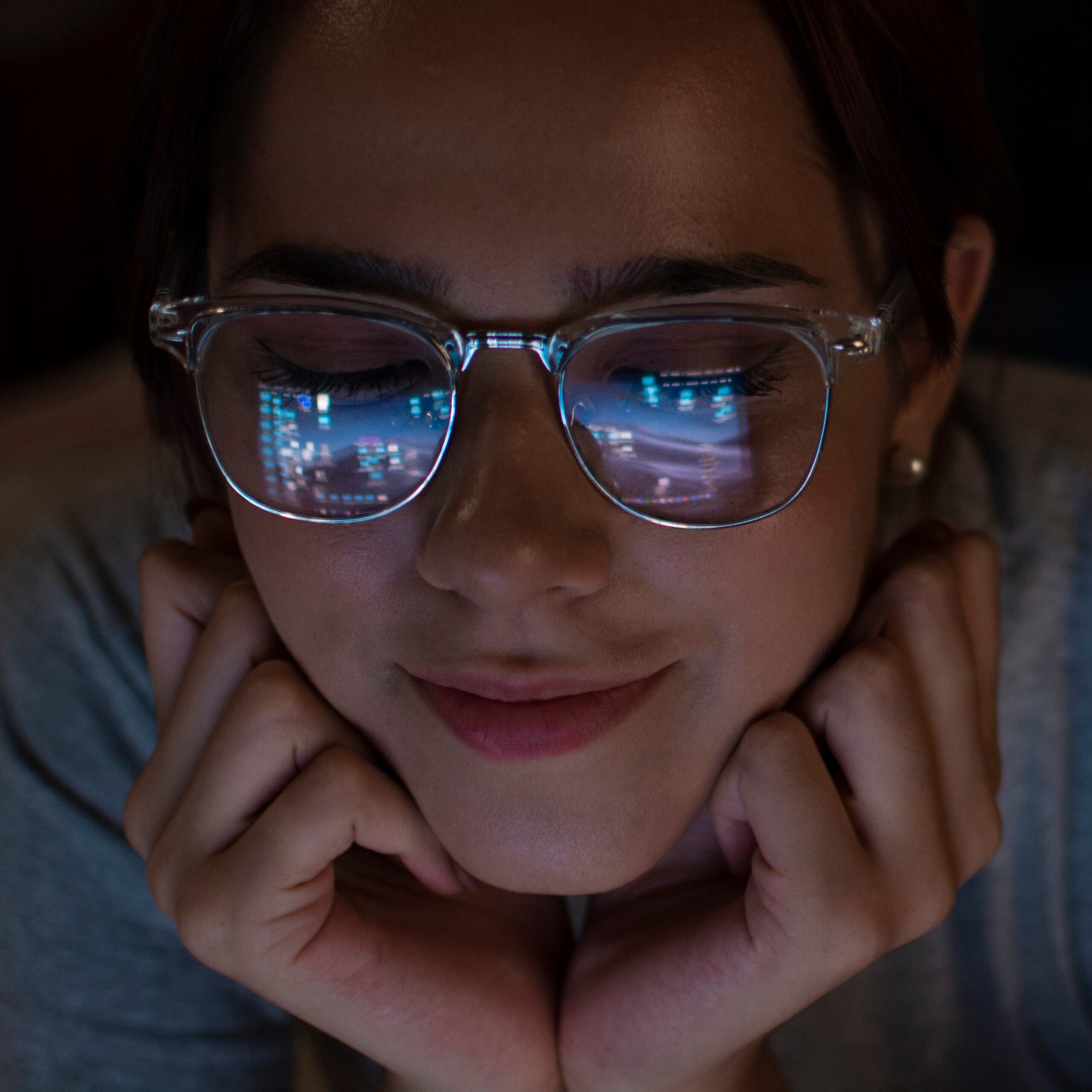 Woman staring into a screen with digital icons reflected in her glasses, illustrating the paradox of attention seeking and ADHD through a psychoanalytic lens.